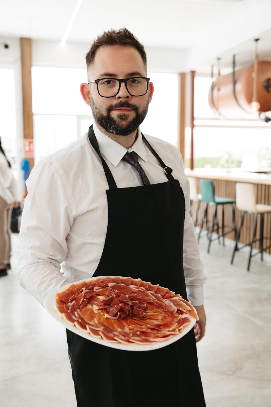 Adrián, maestro cortador de jamón en Murcia, sosteniendo un plato de jamón ibérico recién cortado